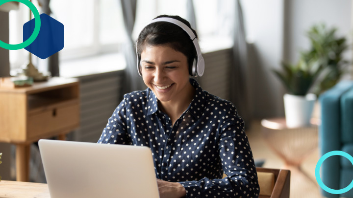 Smiling woman wearing headphones and using laptop